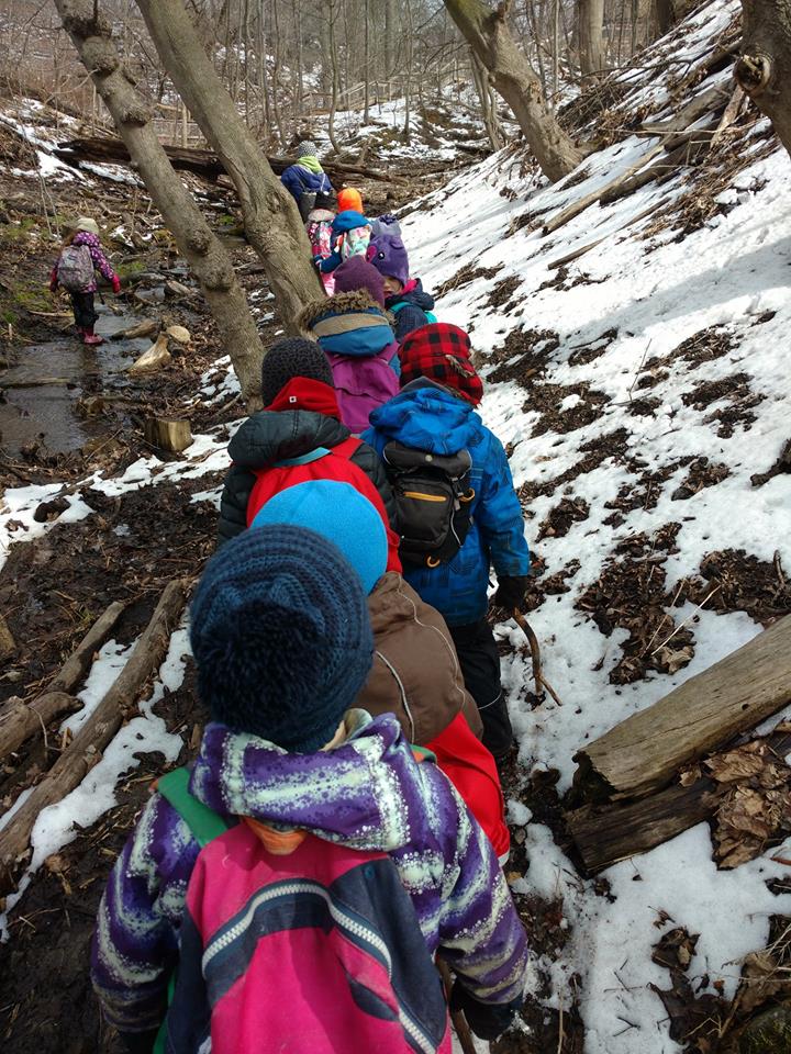 students walking in a line through a local ravine in winter